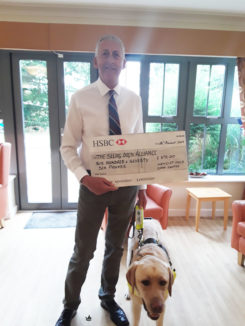 Representative and dog from The Seeing Dogs Alliance accepted a charity cheque at Hengist Field Care Home