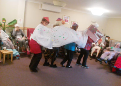 Staff under a Chinese Dragon costume, performing for residents in their lounge