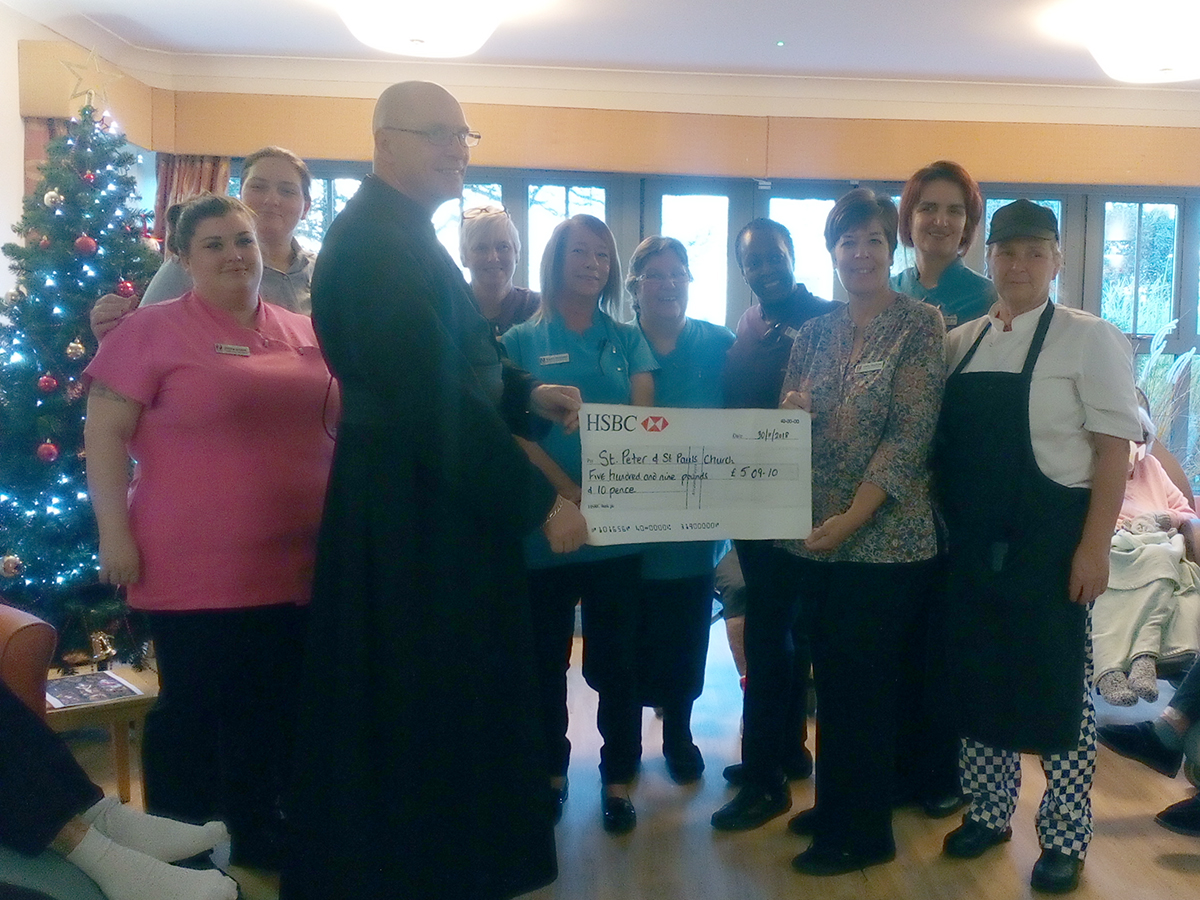 The Hengist Field Care Home staff team presenting a cheque to Father Robert from St Peter and St Paul Church in Borden