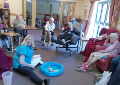 Seated residents in their lounge, watching baby ducks in a small paddling pool