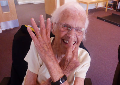 Hengist Field female resident playing a fun game while doing a seated exercise class
