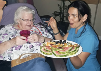 Staff offering a resident a plate of delicious fresh fruits