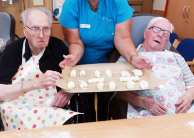 Residents and staff member showing the sausage rolls they have made