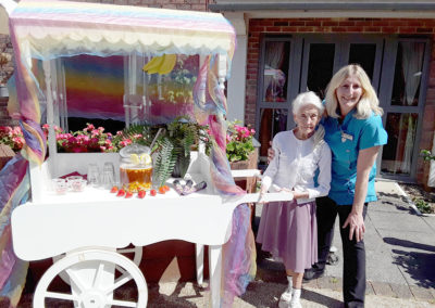 Staff member with a resident next to a drinks trolley outside at Hengist Field