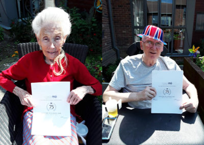 Two residents holding VE Day themed activity booklets