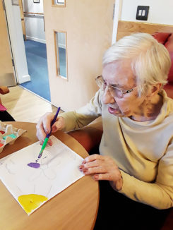 Hengist Field Care Home resident painting onto fabric with paint