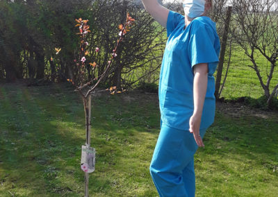 Hengist Field Care Home staff member showing off the newly planted Jubilee cherry blossom